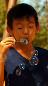 Vertical video: Dipping wands into solution two boys blowing bubbles on playground for fun