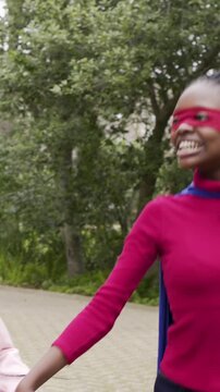 Vertical video: Heading costumed sisters raising pumpkin buckets on path with host extending candy