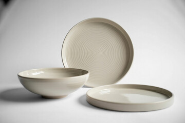 Minimalist ceramic dinnerware set with plates and bowls on a white background