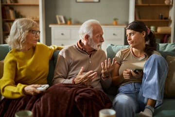 Obraz premium Senior parents feeling frustrated while their adult daughter is using cell phone at home