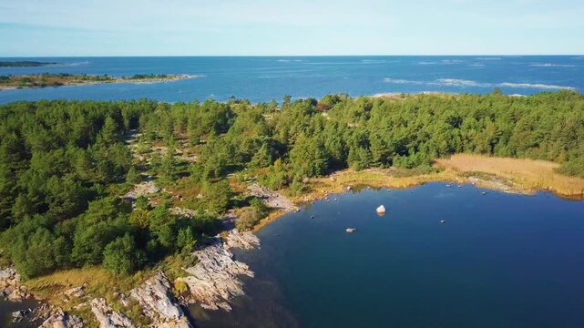 Aerial drone footage flying over Finnish Baltic archipelago islands in autumn with rocky shores, calm blue water and colorful forests. Ideal for travel, nature and scenic landscape themes