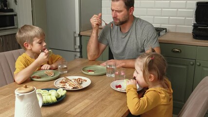 Family dinner. Children enjoy grilled meat with vegetables. Father and children share cheerful meal at their kitchen table. Warm home setting. Dad and kids eating together at home. Casual atmosphere. - Powered by Adobe