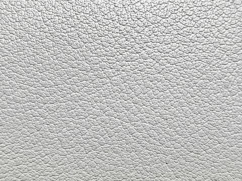 close-up of white pebbled leather texture with detailed fine grain and soft bumpy surface in light gray shades on pale background abstract image