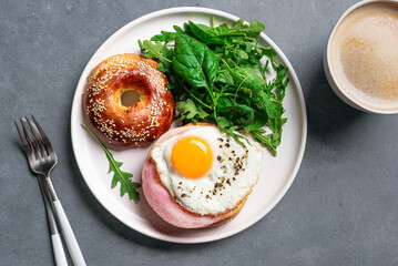 Healthy breakfast. Bagel sandwich with fried egg, ham and greens