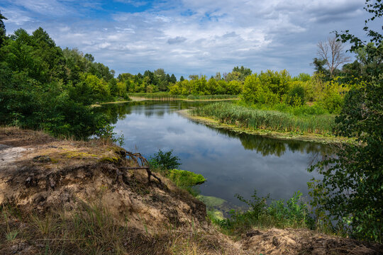 steep sandy cliff with lush greenery above a bend in the river