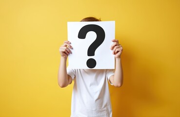 Young person holds white paper with big question mark, covering face. Yellow background. Child shows curiosity, doubt, indecision about an unknown problem. They seek answers and clarity.