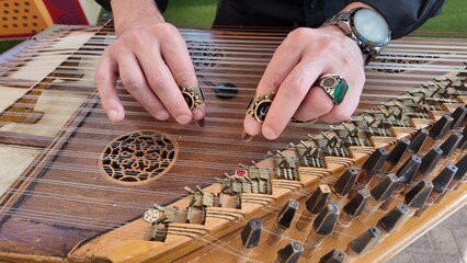 man playing qanun, traditional turkish instrument, kanun, turkish man performing wooden string instrument in Al Ain Zoo Celebration of Independence Day of the UAE.2 December 2025	
