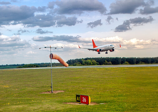 Passenger jet approaches runway near windsock at London Luton Airport