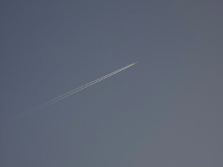 Airplane contrail with clear blue sky creating a minimal tranquil background for travel themes