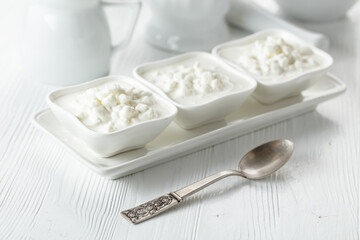 Cottage cheese with cream on a white table.