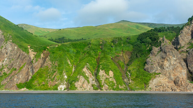 A view of the rocky coast of Sakhalin Island, along which five waterfalls flow into the sea. - Powered by Adobe