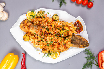 Top view of sweet and sour fish with crispy crust and lemon - appetizing dish on grey background
