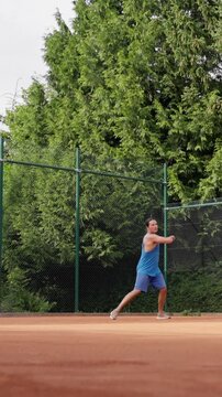 male caucasian tennis player backhand return, compact twohanded backhand, balanced stance, clay dust, steady footwork, overcast sky, green fence and shrubs, blue athletic outfit, club practice