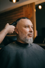 Portrait Caucasian mature male getting haircut at barbershop