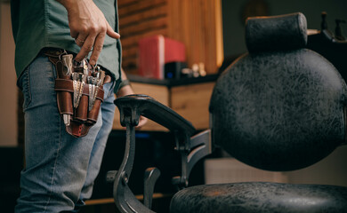 Barbershop interior with male stylist holding tools near chair