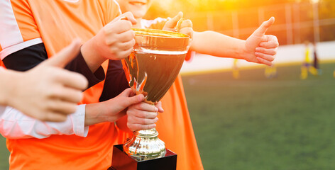 womens childrens football team celebrating victory with trophy at sunset