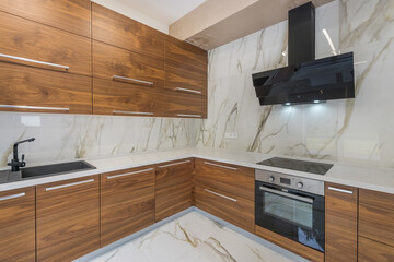 The kitchen features wooden cabinets and a marble countertop. A black stove and hood are installed...