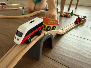 child playing with toy trains on wooden floor, concept of toy store, kids entertainment, education.