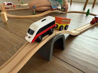 child playing with wooden train set on floor at home concept of toy store, education, family
