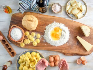 Someone is making fresh girasoli pasta. Eggs are in flour, and pasta and cheese are displayed on a rustic wood board. Sunlight streams in during the afternoon, creating a warm ambiance