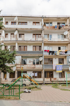 Vayk, Armenia - 16 August 2025: View of an aged apartment building with satellite dishes, clotheslines, and a children's playground, a scene of everyday life.