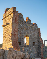The thousand-year-old remains of the Rocca di Campiglia: the keep, the ancient cistern, and the imposing crenellated walls with mullioned windows of the noble palace. Tuscany, Italy