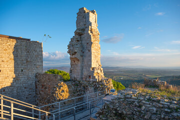 The thousand-year-old remains of the Rocca di Campiglia: the keep, the ancient cistern, and the imposing crenellated walls with mullioned windows of the noble palace. Tuscany, Italy