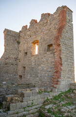 The thousand-year-old remains of the Rocca di Campiglia: the keep, the ancient cistern, and the imposing crenellated walls with mullioned windows of the noble palace. Tuscany, Italy