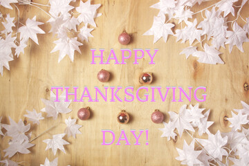 A wooden background with white Christmas leaves,Christmas baubles, and a Happy Thanksgiving Day phrase