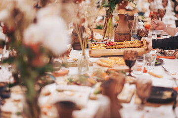 Gathering of friends at a long table filled with various dishes and drinks during a festive meal in a cozy setting