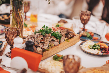 Group of people enjoying a meal with various dishes at a table during a gathering in a warm indoor setting in the evening