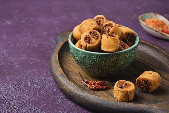 Salty Indian cookies bhakar badi with chickpea flour and spices filling in a green ceramic bowl