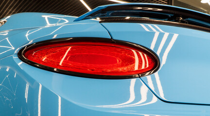 Red LED turn signal in the rear brake light of the car. Modern car lantern, close-up. Detail on the rear light of a sky blue car. Close-up of a modern blue SUV automobile with LED red taillights.