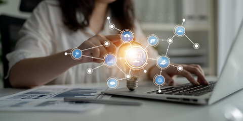 A business professional engages with a digital network, symbolizing innovative ideas through a light bulb, enhancing productivity in an office setting. Tessel