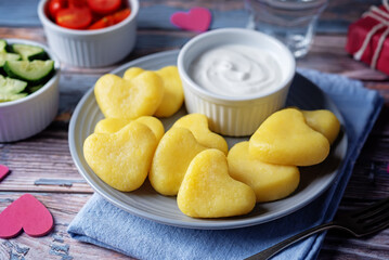 Potato gnocchi in the form of hearts with cream sauce for Valentine's day holidays on a wood background