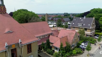 Aerial view of quiet European neighborhood with sloped roof homes, cyclists, greenery, and a central road marked 30 a peaceful, well kept suburban scene with symmetry and charm.