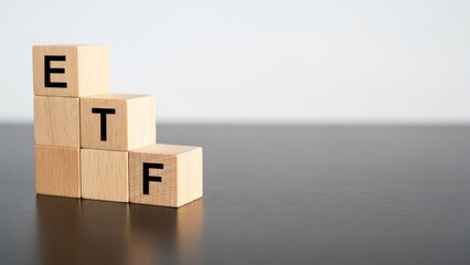 Fototapeta premium Letters ETF on wooden blocks forming a staircase on a dark table with a white background