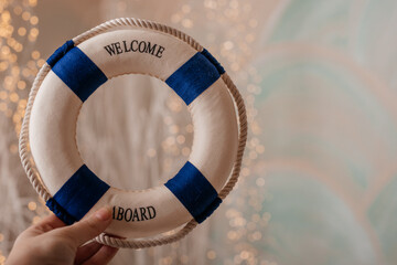 Decorative blue and white lifebuoy with the word &ldquo;Welcome,&rdquo; photographed in a cozy nautical setting.