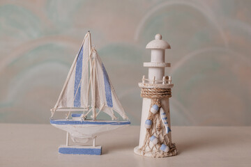 Small nautical-themed figurines of a sailboat and a lighthouse placed on a light surface.