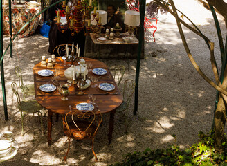 Wooden outdoor table in a garden courtyard set with vintage plates