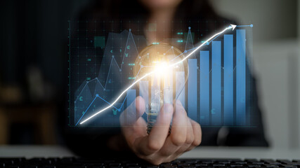 A business person holds a light bulb symbolizing innovation, with a digital chart displaying growth trends, representing progress and success in a corporate setting. Impute