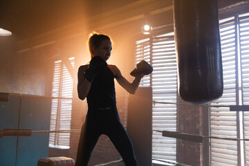 Women self defense girl power. Strong woman fighter training punches on boxing ring. Healthy strong girl punching boxing bag. Training day in boxing gym. Strength fit body workout training