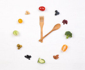 Intermittent fasting concept, spoon and fork with small portions of food looking as a clock on a white background