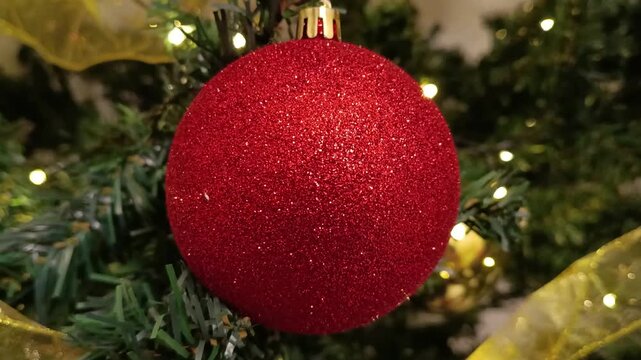 Close-up shot of perfect Christmas decoration with accessories and green New Year tree with red Christmas decoration and lights on its branches.