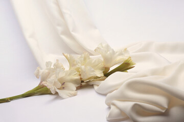 White beige drapery Wave Fabric Silk podium, gladiolus Flower twig. Abstract light and shadow texture art background.