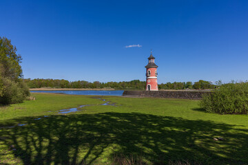 Historical Moritzburg Lighthouse on the shore of the Castle Pond. Red facade and turquoise roof against a blue sky and forest