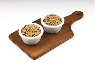 Green lentils in wooden bowl on isolated white background. Top view, copy space. Flat lay. (real photo. NOT artificial intelligence generated.)