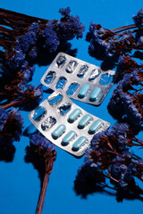 blue pills and flowers on blue background
