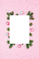 Christmas, New Year vertical frame of fir tree branches, Christmas baubles, decorations on pink and white flat lay background. Perfect for holiday greetings, banners, social media. Copy space