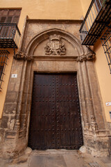 Historic carved stone doorway with a wooden medieval-style door and ornate coat of arms in Valencia, Spain, showcasing traditional architecture and cultural heritage.